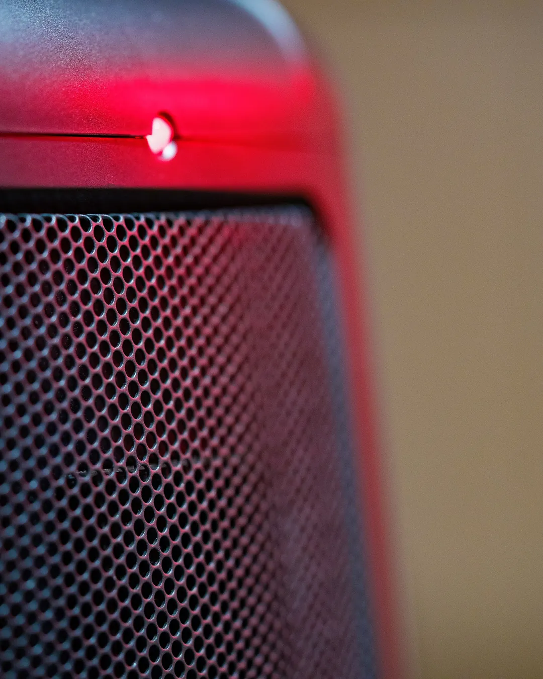 Detalle de la rejilla negra de un calefactor eléctrico encendido, con un piloto rojo iluminado en la parte superior