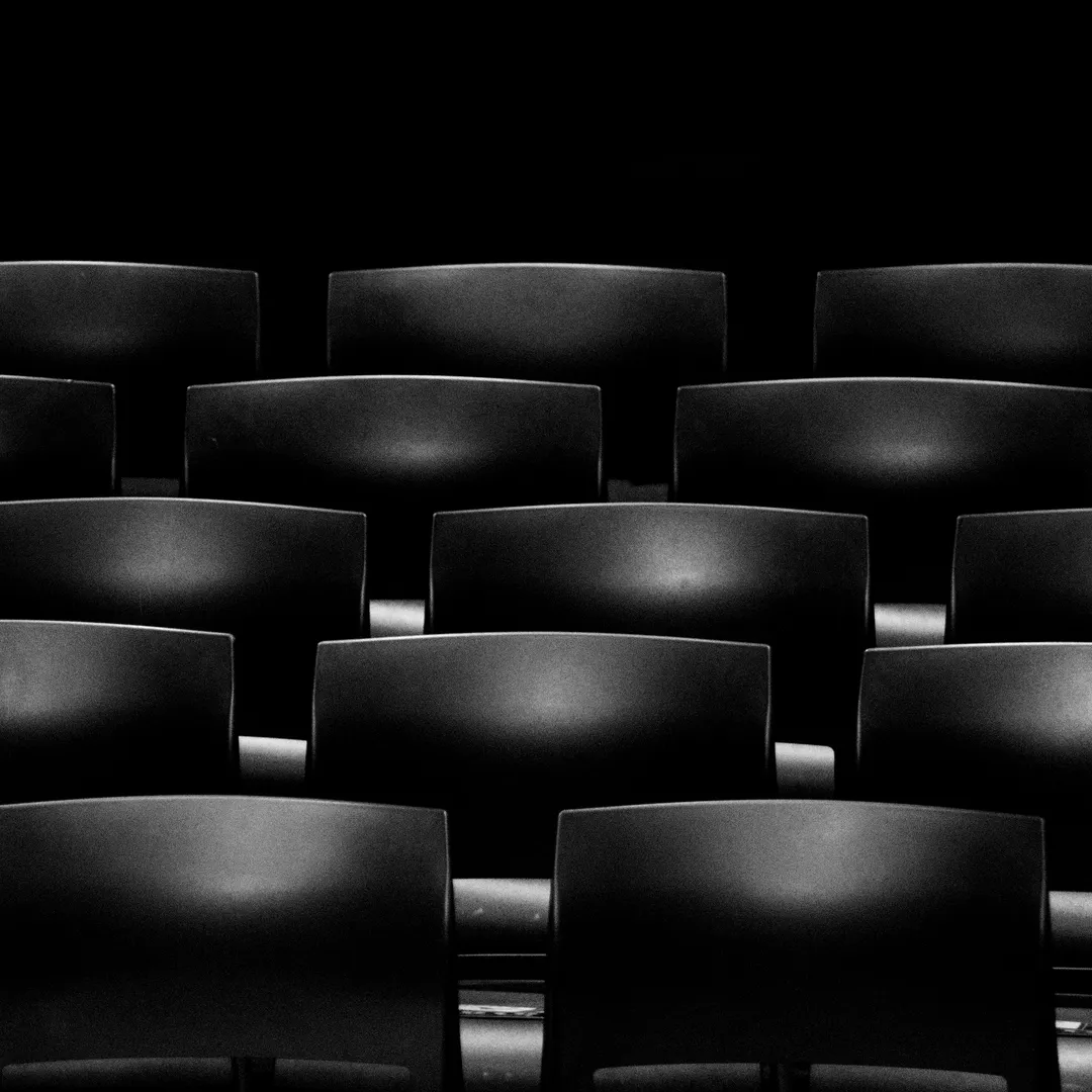Filas de butacas negras de un cine a oscuras