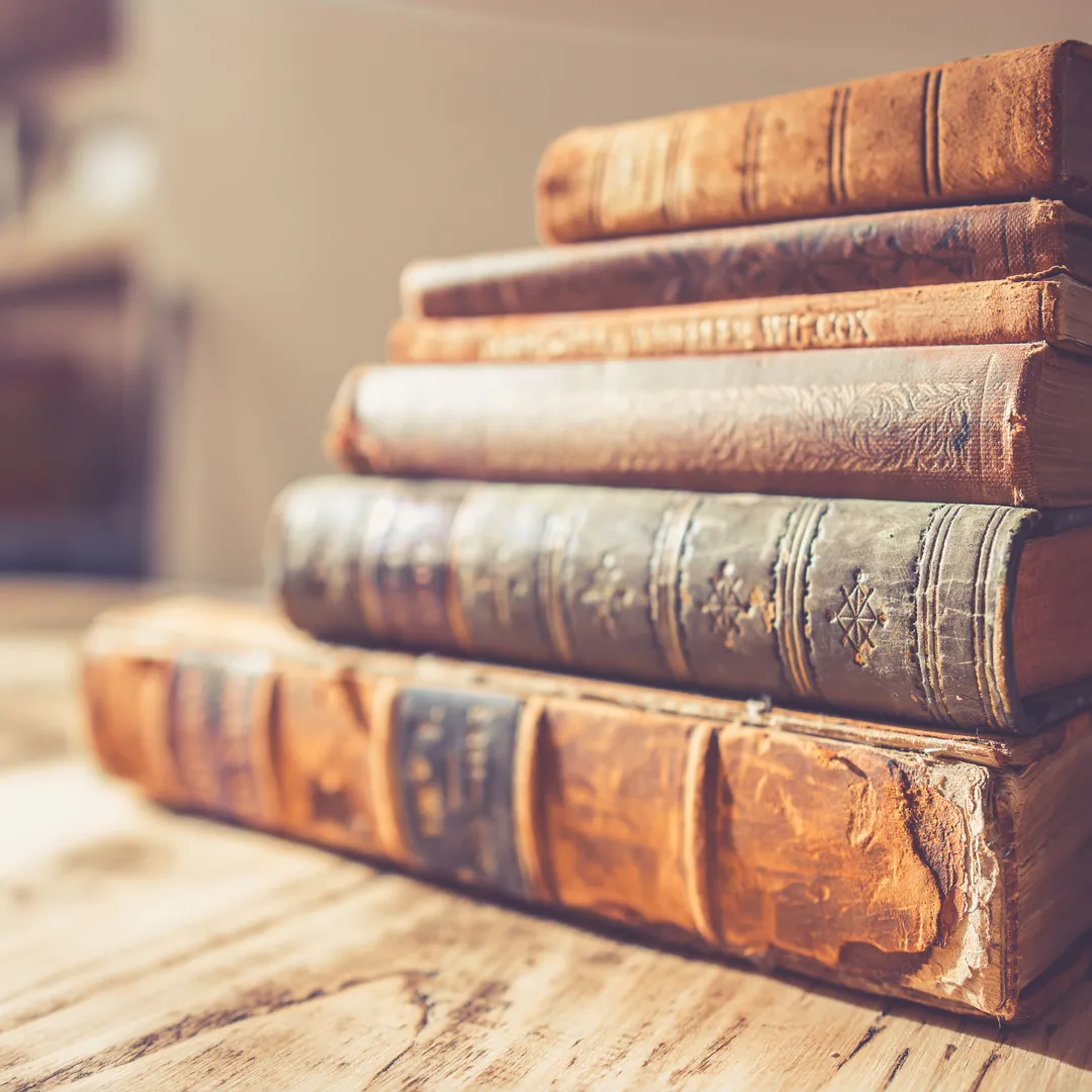 Pila de libros antiguos encuadernados en piel sobre una mesa