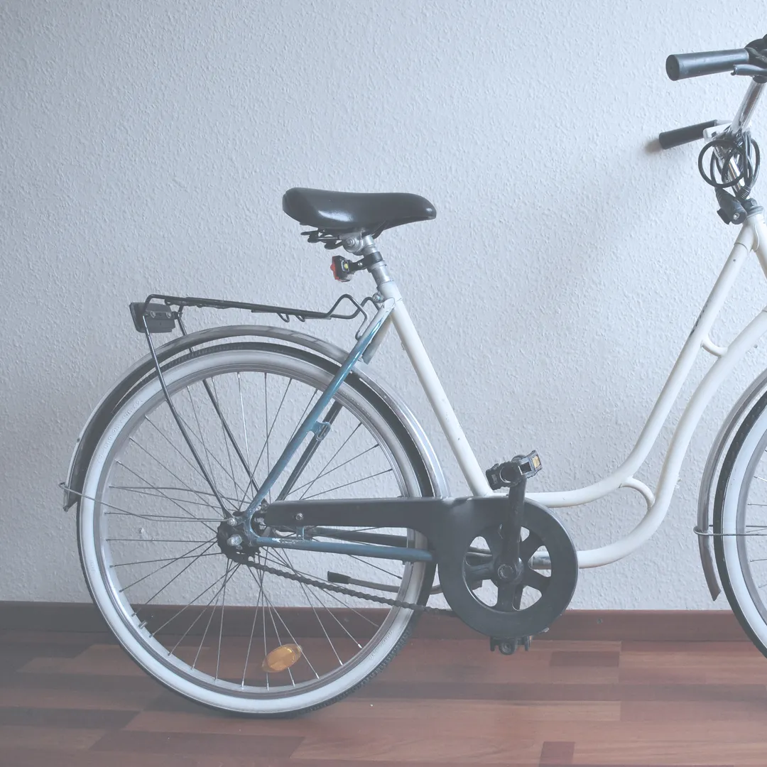 Bicicleta de paseo blanca apoyada en una pared blanca
