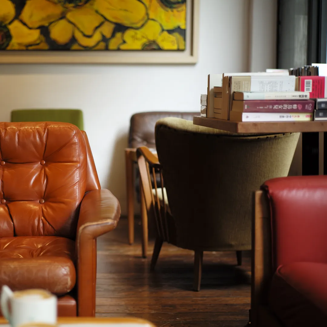 Sala de estar con sillón de cuero marrón, sillas y un cuadro amarillo