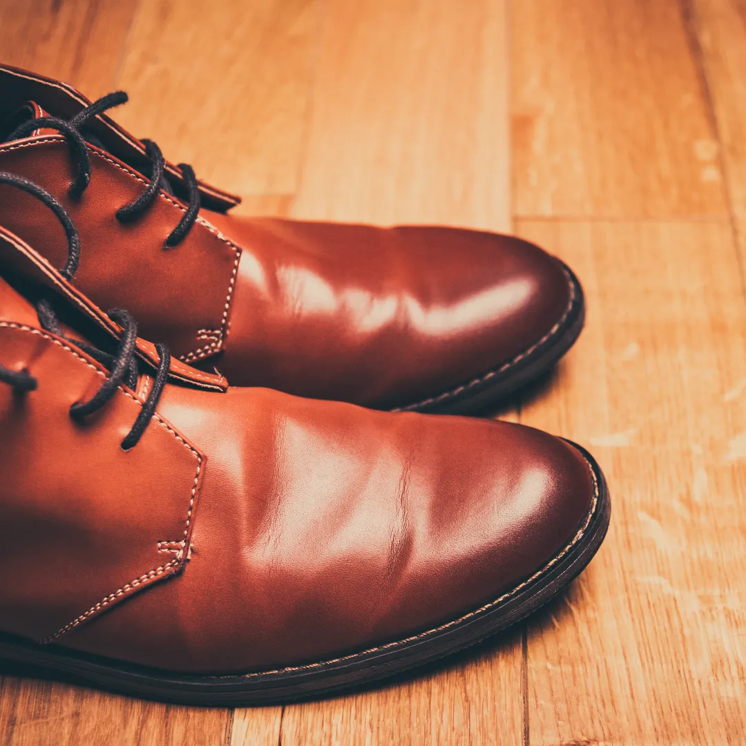 Zapatos de cuero marrón con cordones sobre un suelo de madera