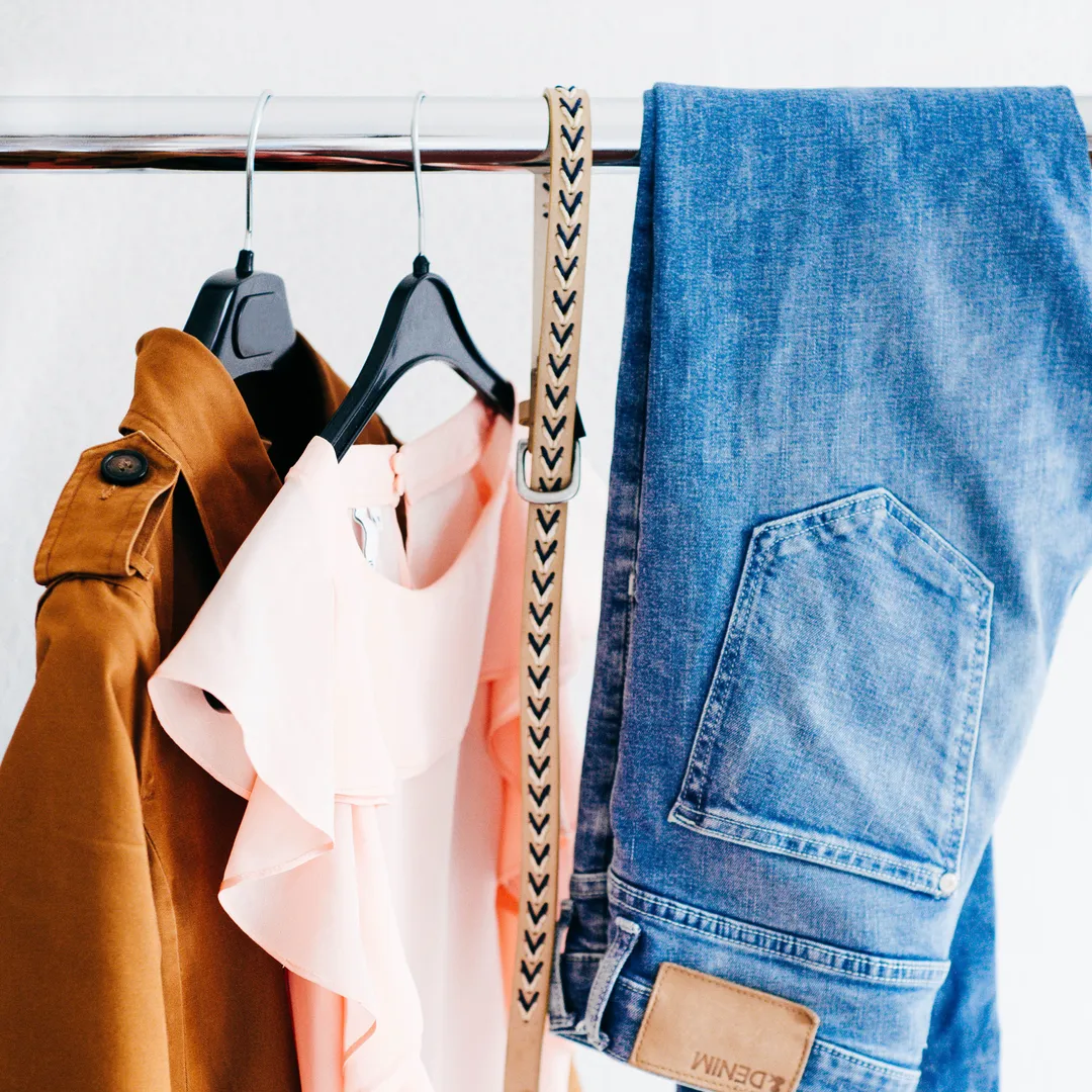 Chaqueta de ante, blusa rosa y vaqueros colgados en perchas