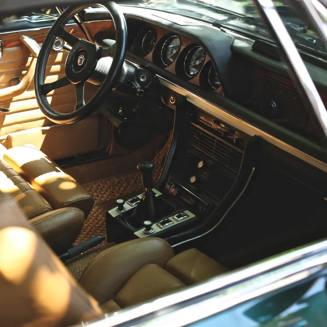 Interior de un coche clásico con volante, salpicadero y asientos de cuero