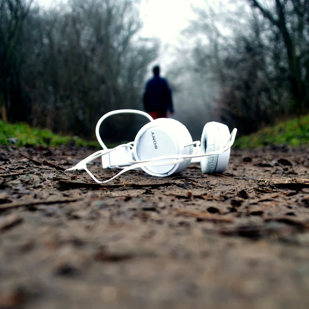 Auriculares blancos sobre un camino de tierra en un bosque