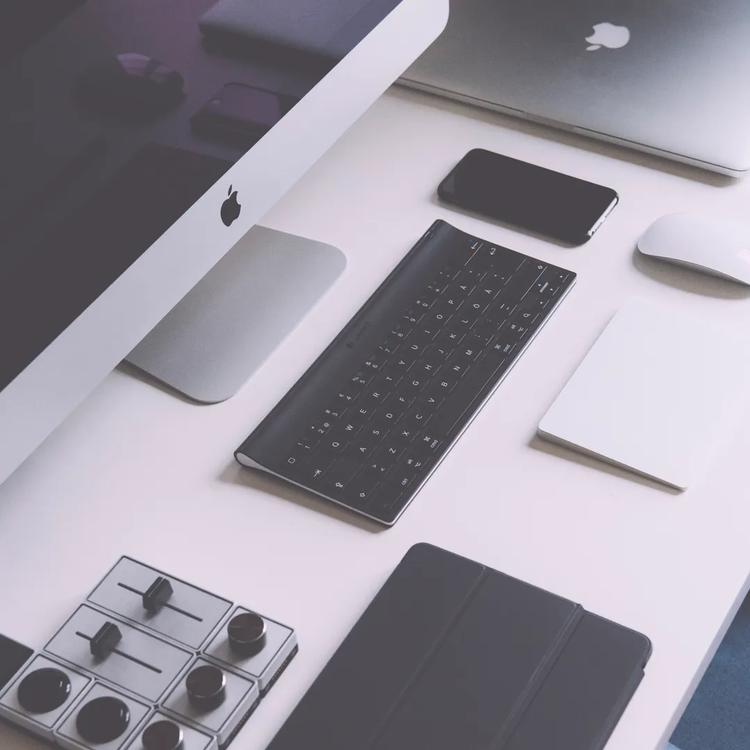 Teclado, tableta, ratón y otros aparatos en gris sobre una mesa blanca