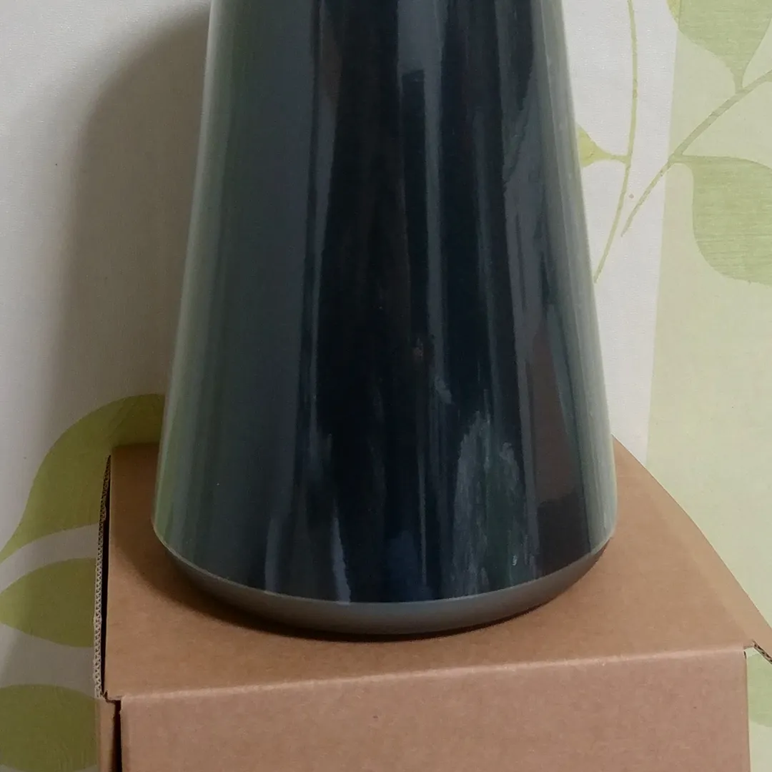 Altavoz cilíndrico oscuro sobre un mueble