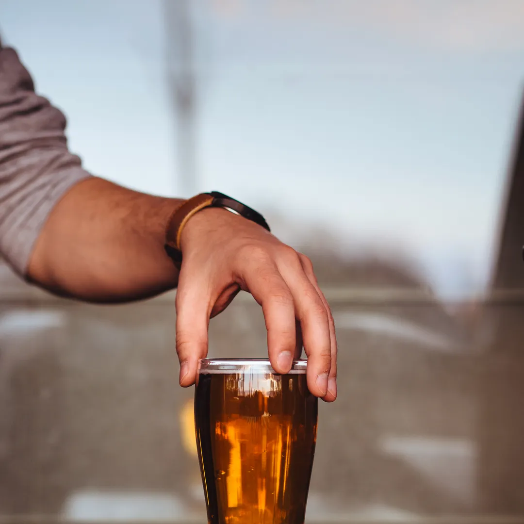Mano sujetando un vaso de cerveza