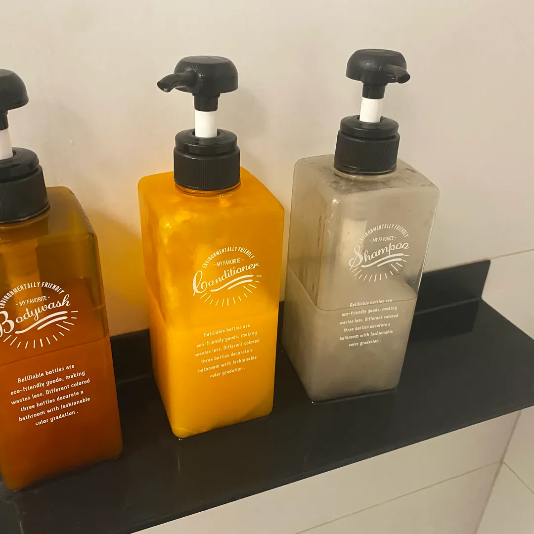 Botellas de champú y gel con dosificador en una balda