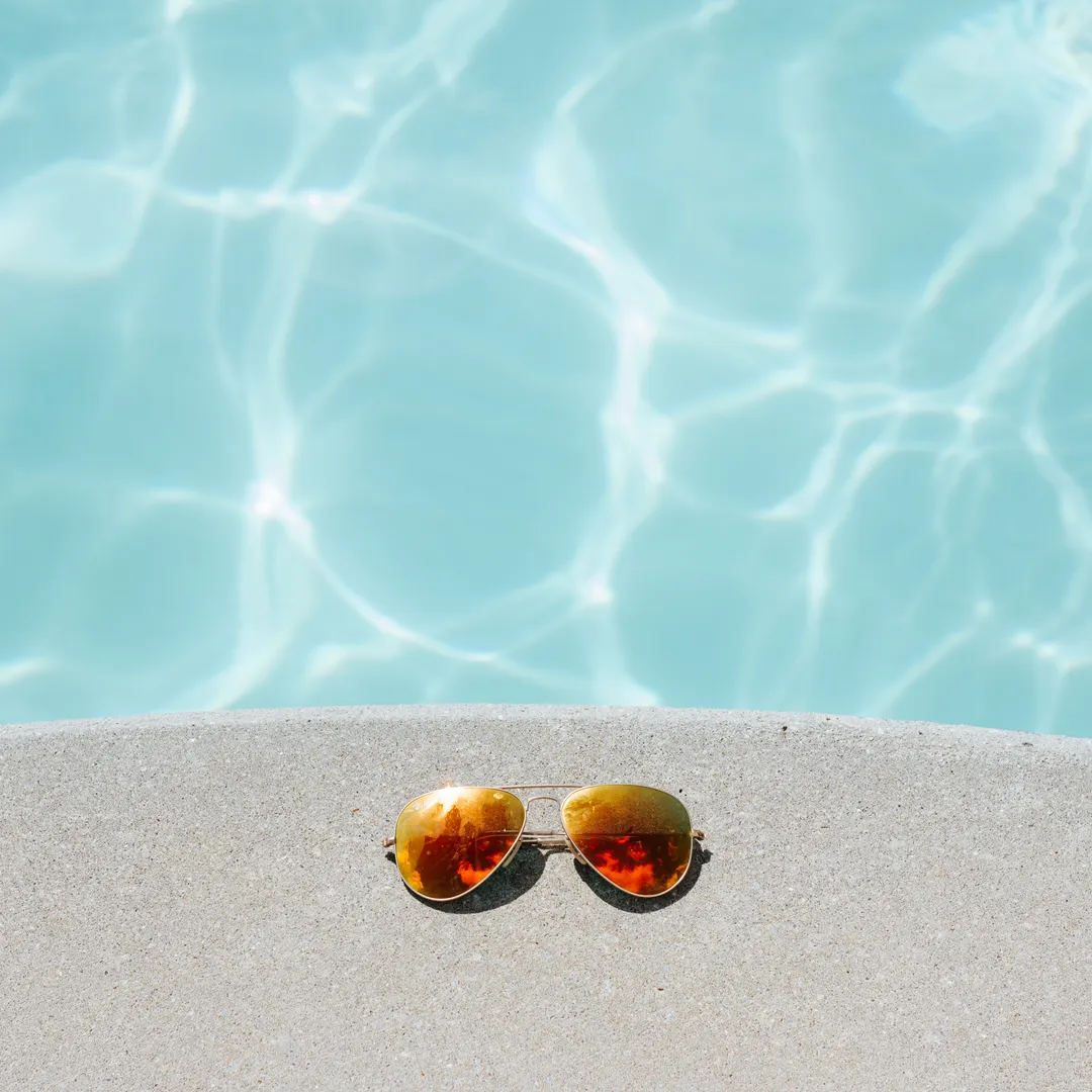 Gafas de sol de espejo junto al borde de una piscina