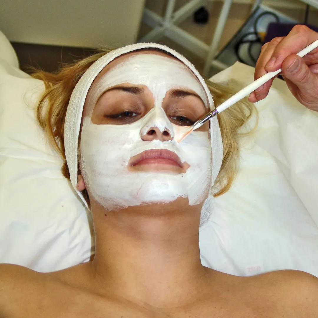 Mujer recibiendo una mascarilla facial con pincel