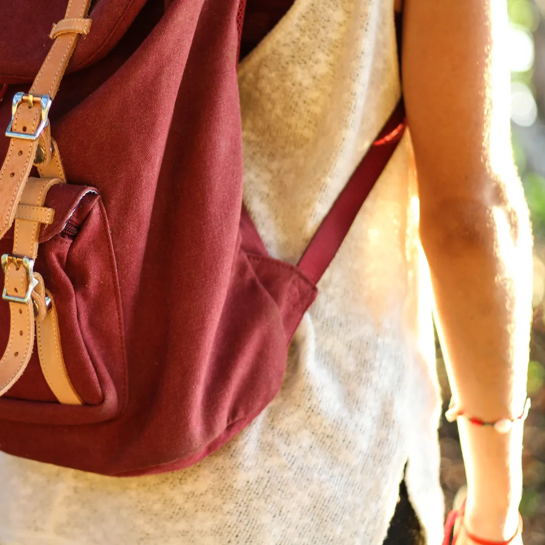 Mochila roja con correas de cuero a la espalda de una persona