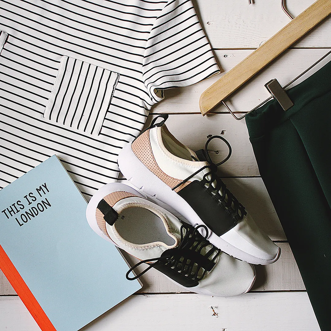 Zapatillas blancas y negras junto a ropa y un cuaderno sobre una mesa